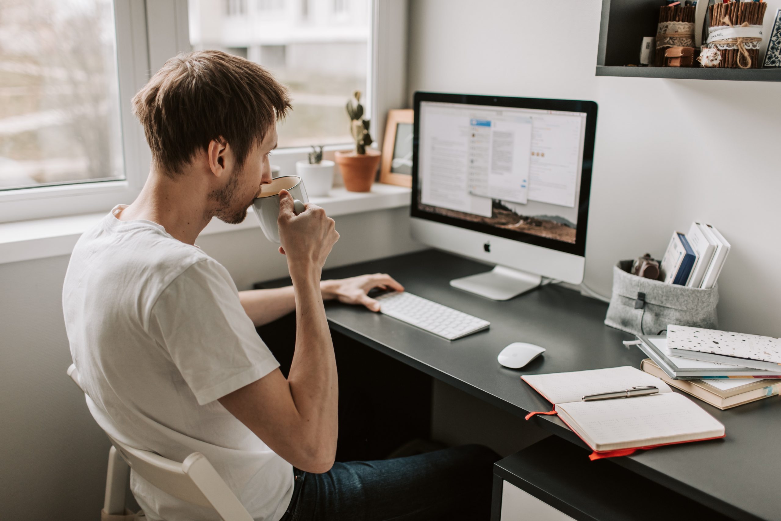 Man at computer sipping coffee