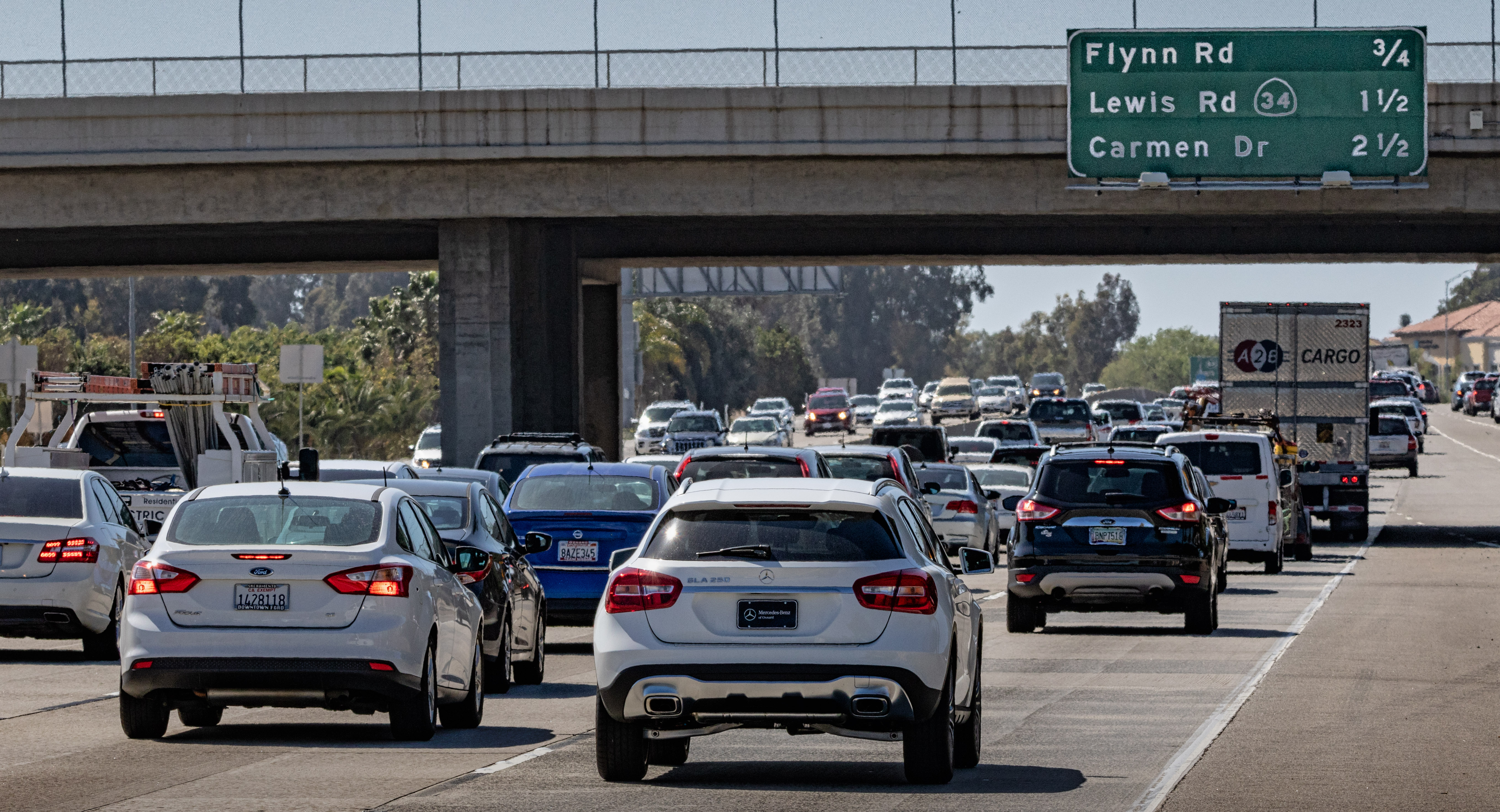 A busy highway with multiple cars and trucks under an overpass on Flynn Rd.