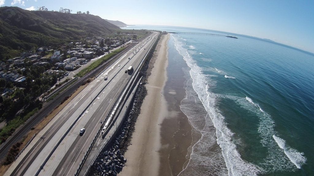 A scenic aerial view of Ventura coastline with highway and ocean waves.