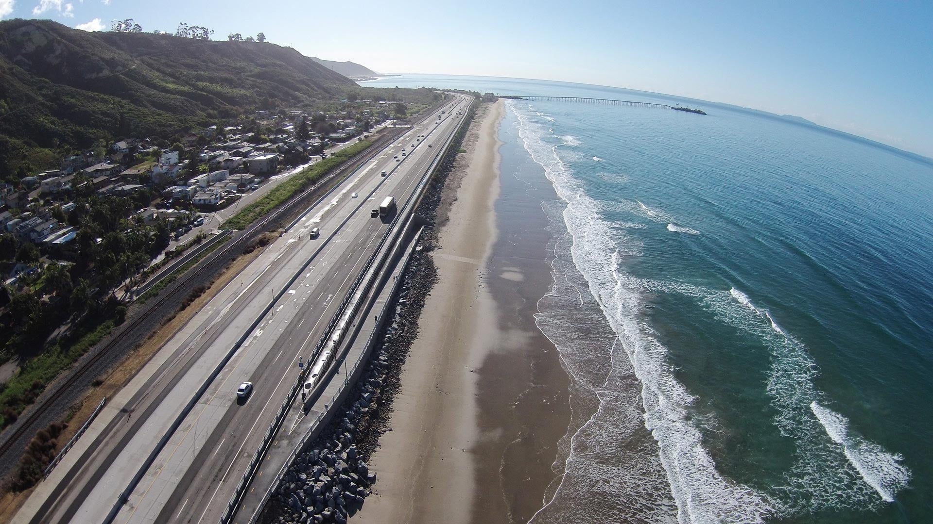 A scenic aerial view of Ventura coastline with highway and ocean waves.