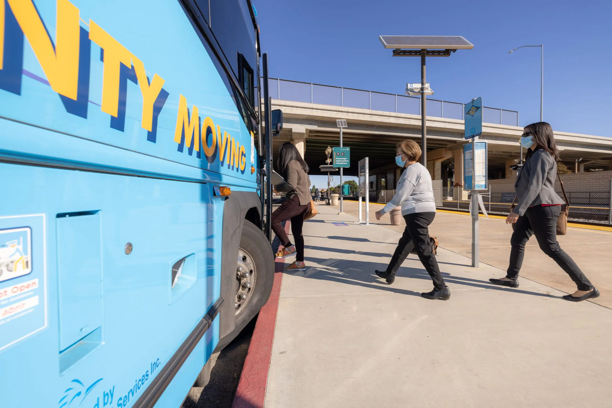 People boarding a city bus at a transit station in Ventura, California.