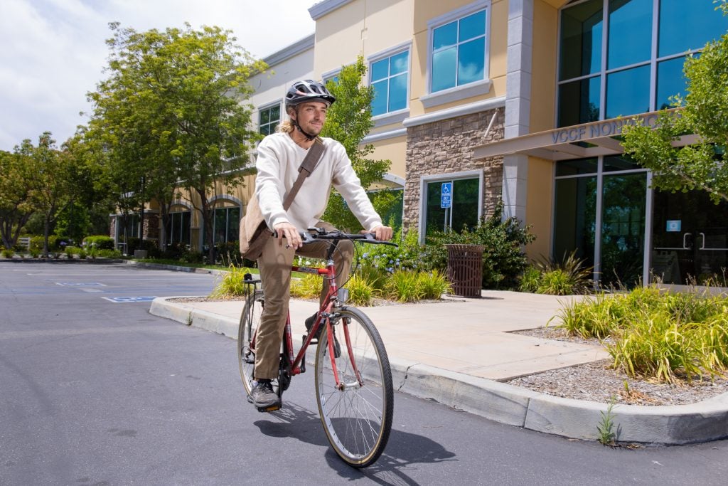Person riding a bicycle outside a modern commercial building in a shopping center.