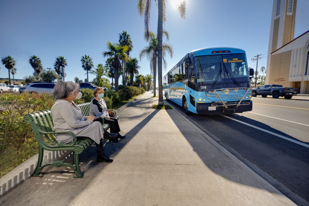 woman at bus stop looking at VCTC bnus