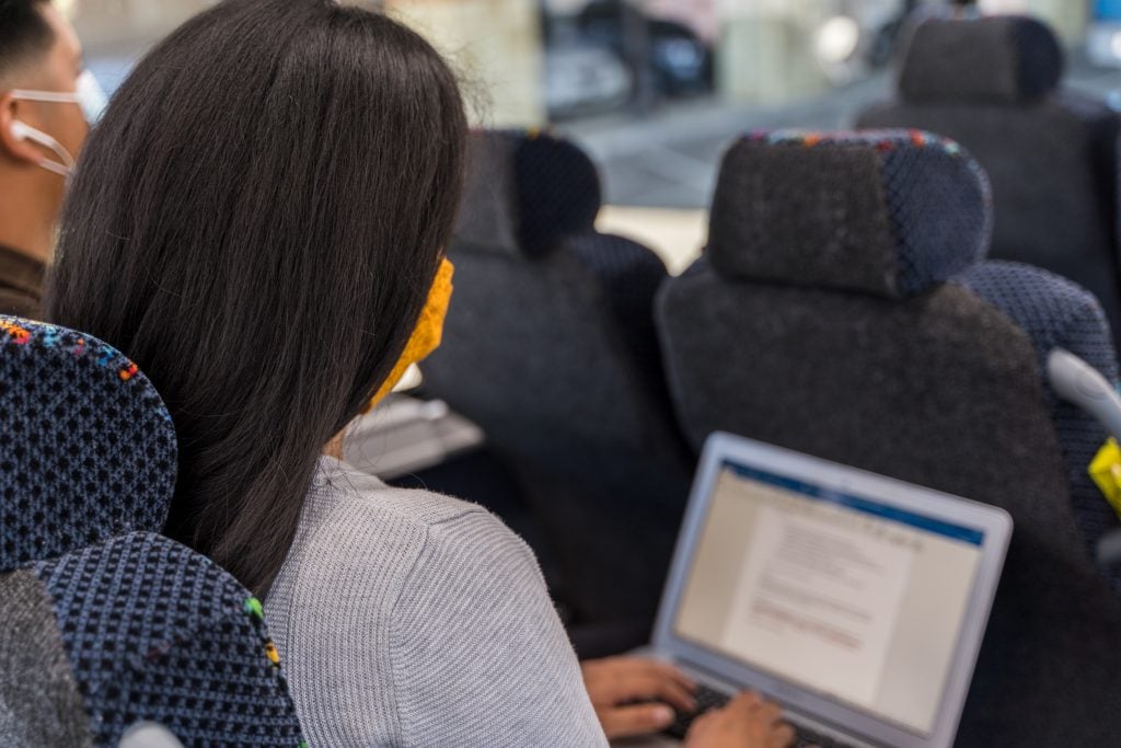 A woman working on a laptop during a bus ride, focused on her task.