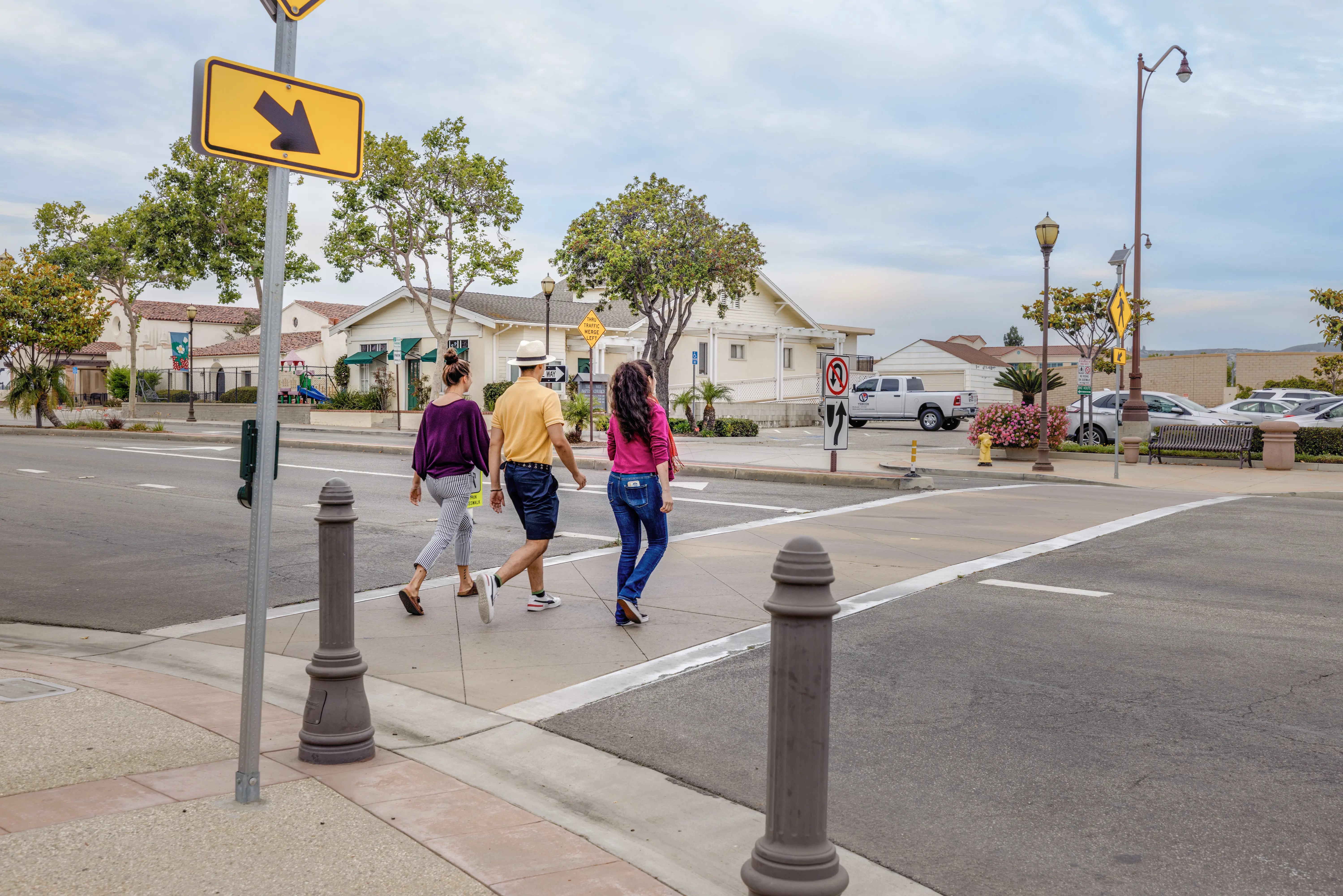 Pedestrians crossing at a marked crosswalk in a suburban neighborhood.