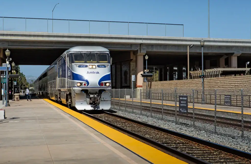 Amtrak train arriving at Goventura station platform in California, urban transit scene.