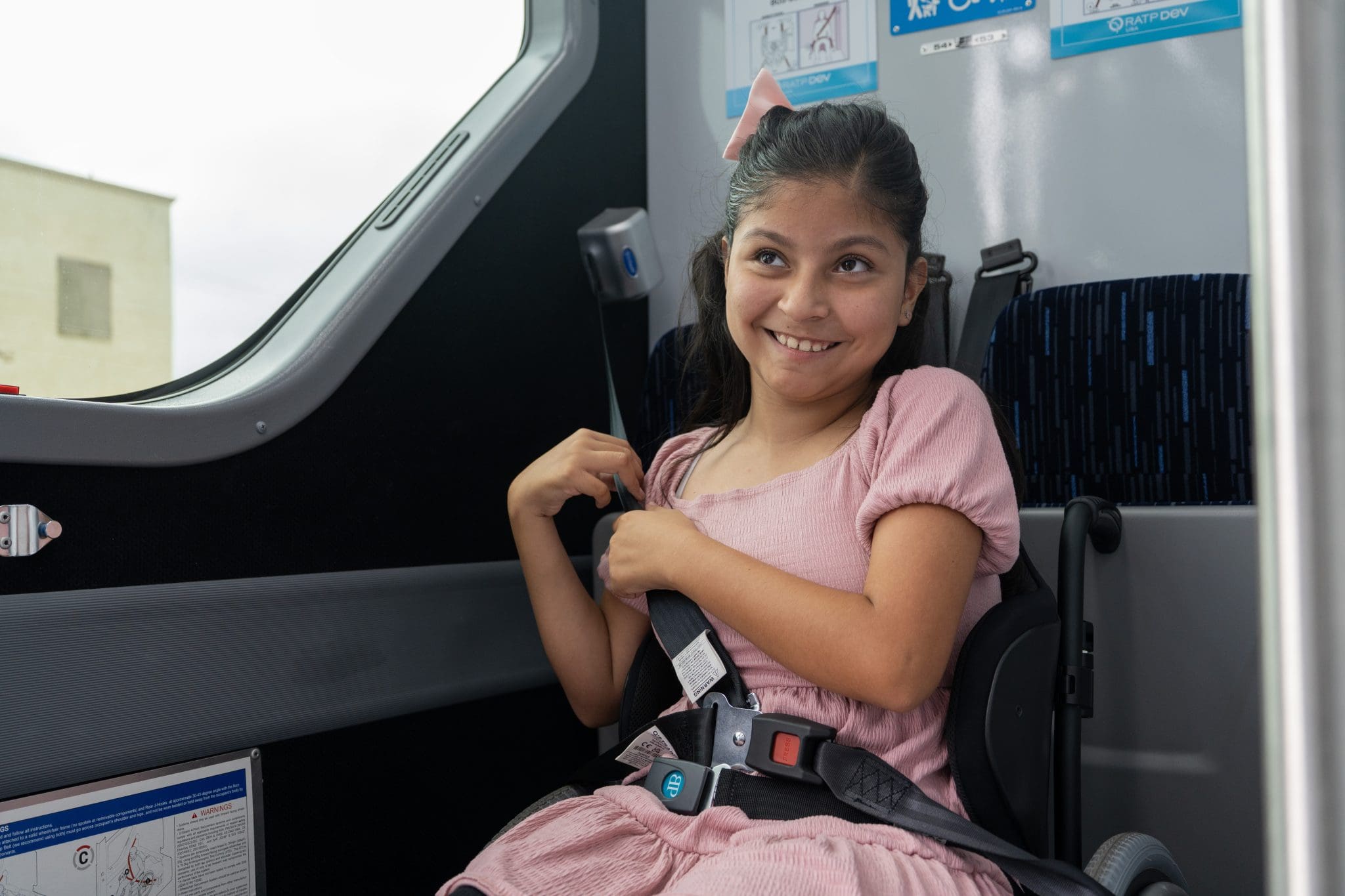 Girl on bus using seatbelt and smiling