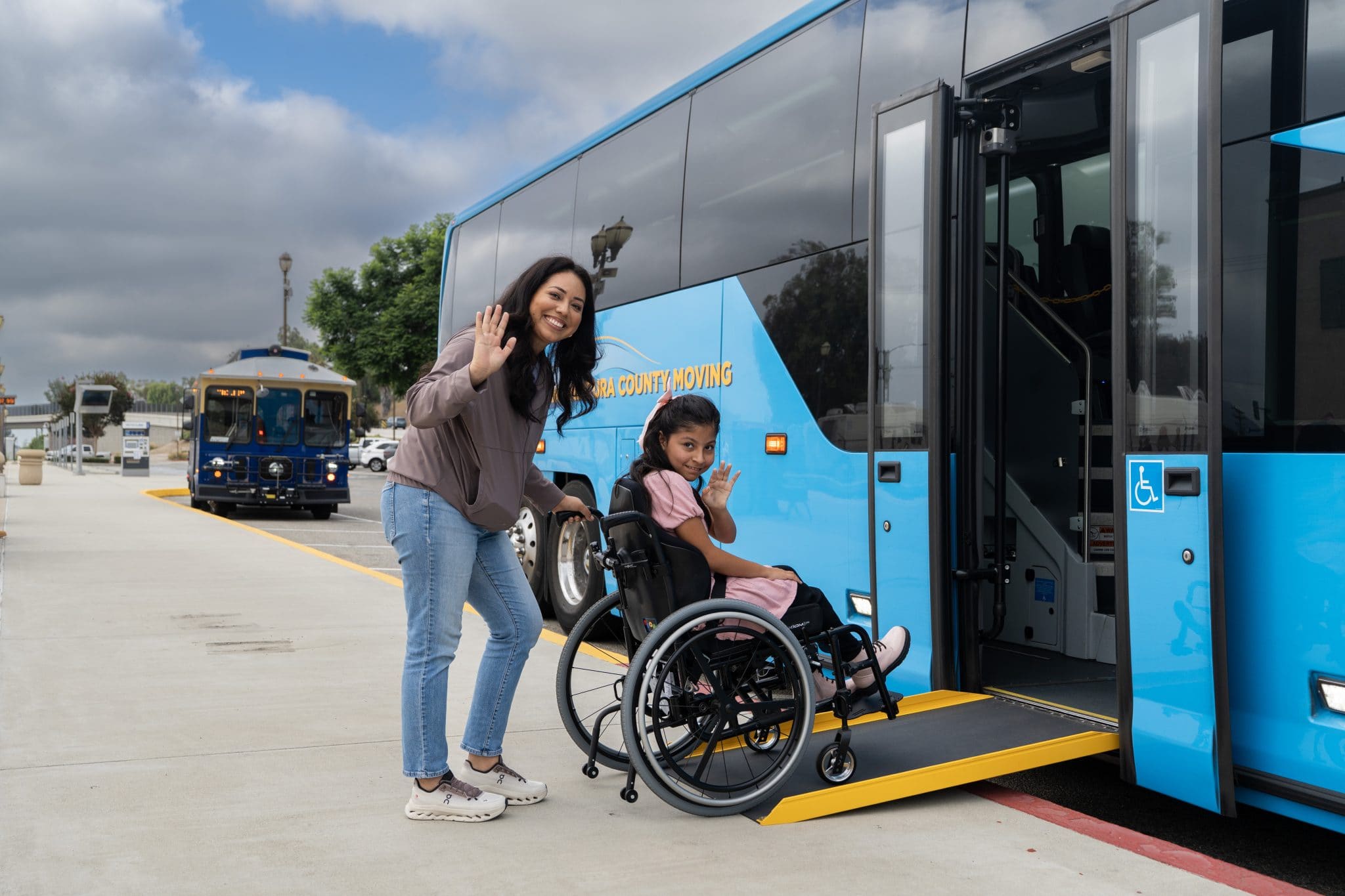Woman assisting girl in wheelchair board the bus