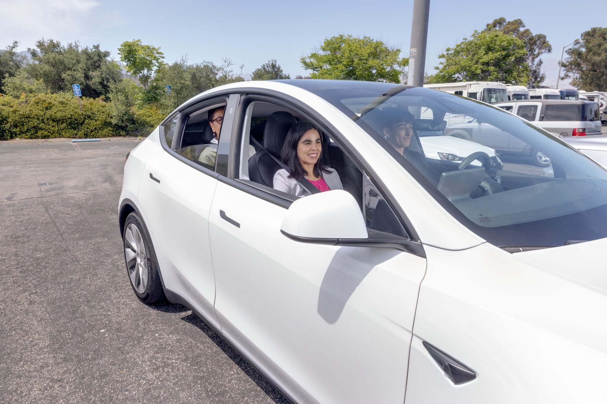 White electric car with smiling woman driver and passengers at Goventura Staging.