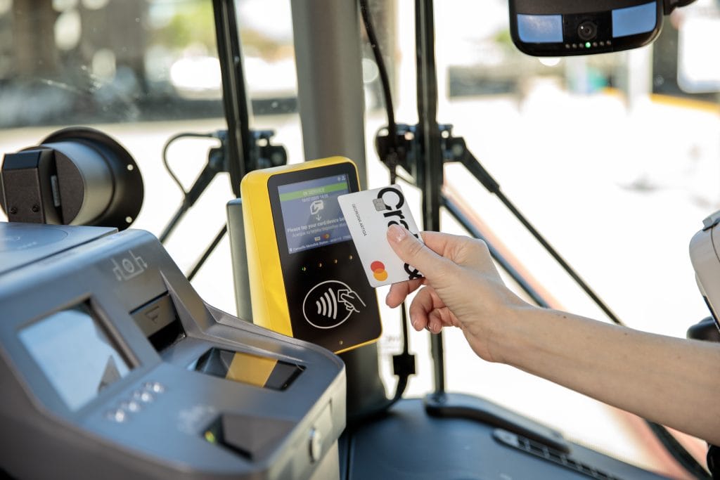 Person using contactless payment on a bus fare machine at Goventura Staging.
