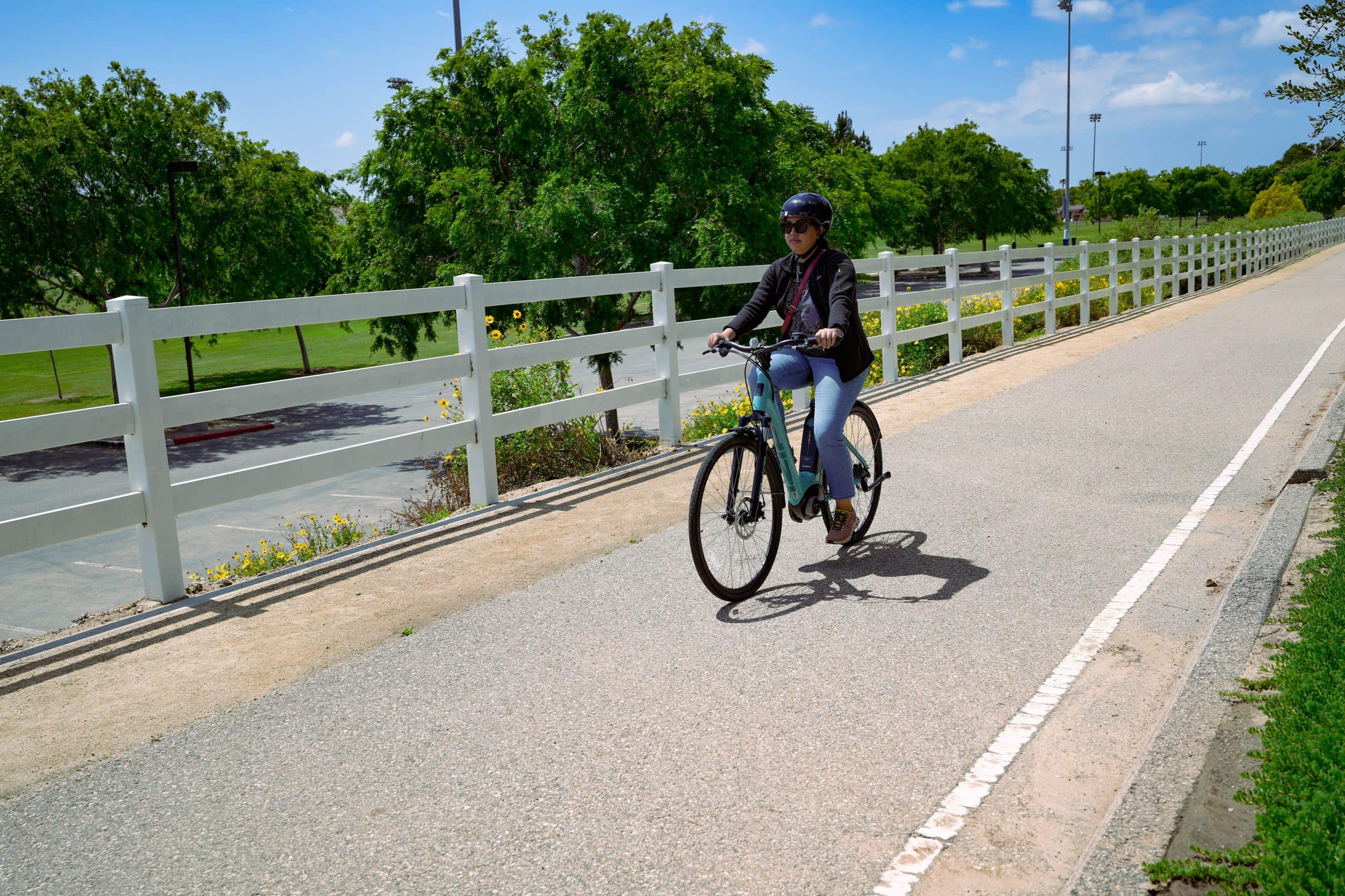 Woman riding a bike on a bike path wearing a helmet